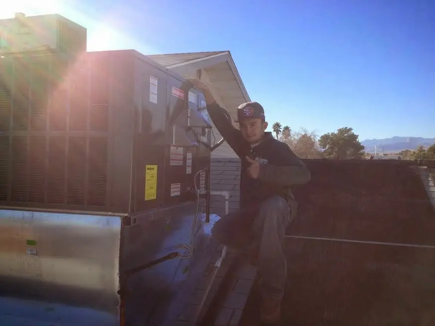 HVAC technician performing Boiler Repair on a rooftop unit in Alliance